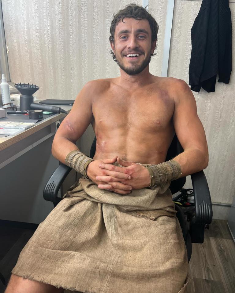 a shirtless man is sitting in a chair and smiling