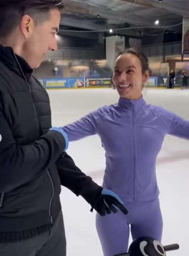 a man and a woman are standing on an ice rink .