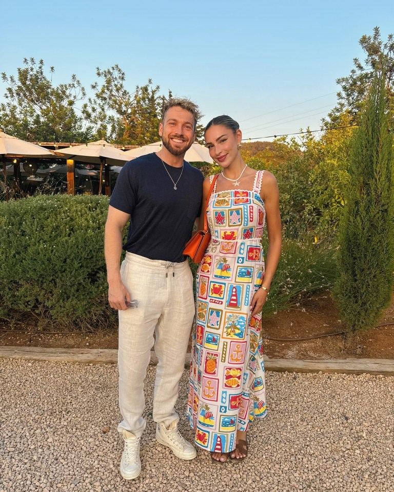 a man and a woman are posing for a picture and the woman is wearing a dress with cards on it