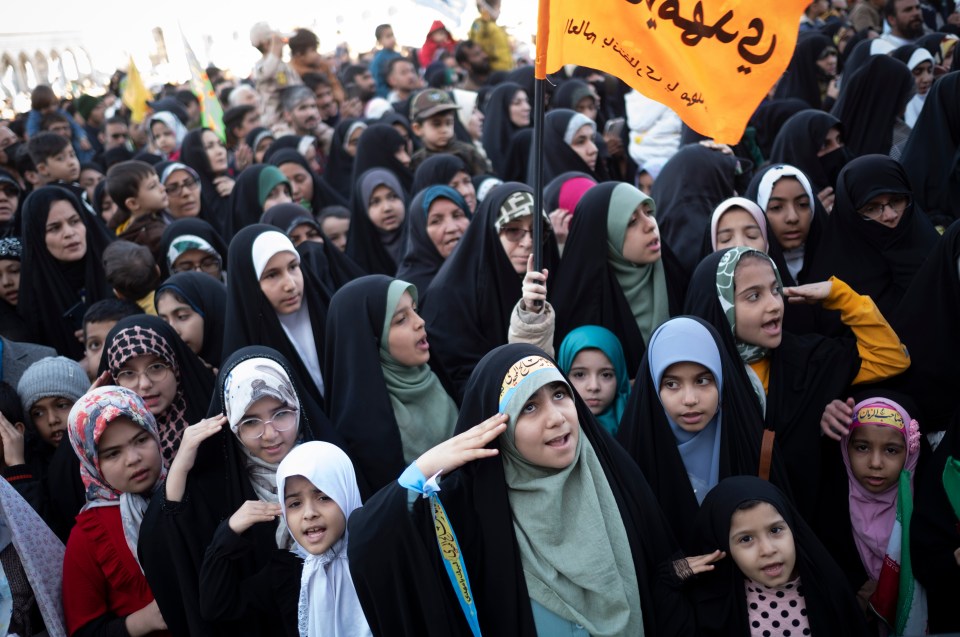 Iranian schoolgirls in veils saluting at a ceremony in Qom.
