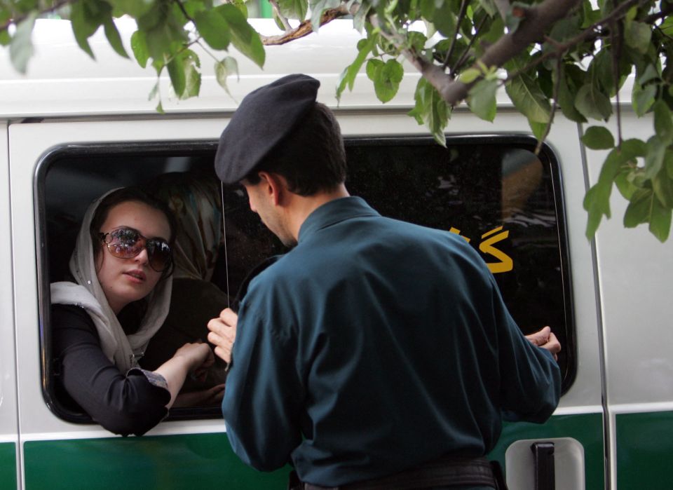 Iranian policeman speaking with a woman in a police vehicle.