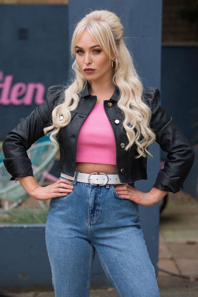 Jorgie Porter in a pink top, black leather jacket, and jeans.