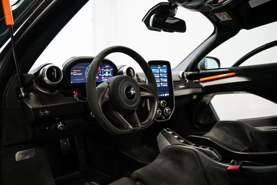 Interior view of a McLaren Senna XP, showing the steering wheel, dashboard, and seats.