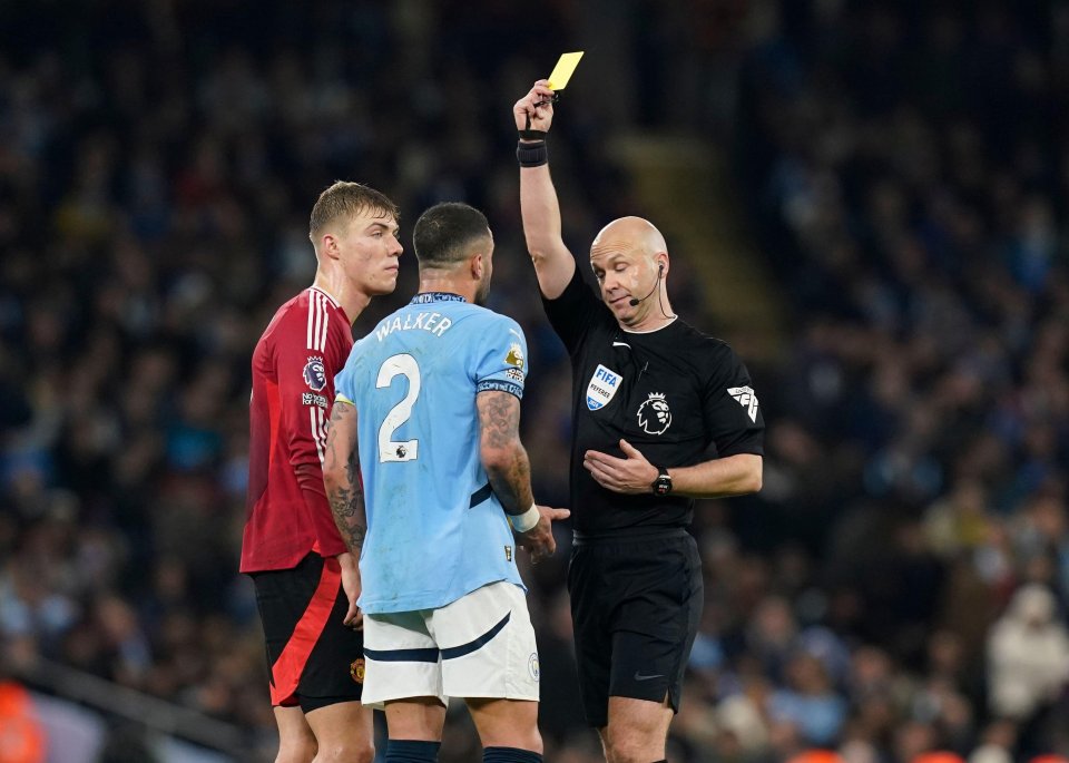Referee Anthony Taylor shows a yellow card to Manchester United's Rasmus Hojlund and Manchester City's Kyle Walker.