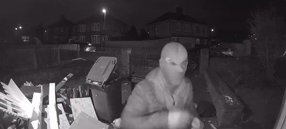 Nighttime security camera footage of a masked burglar.