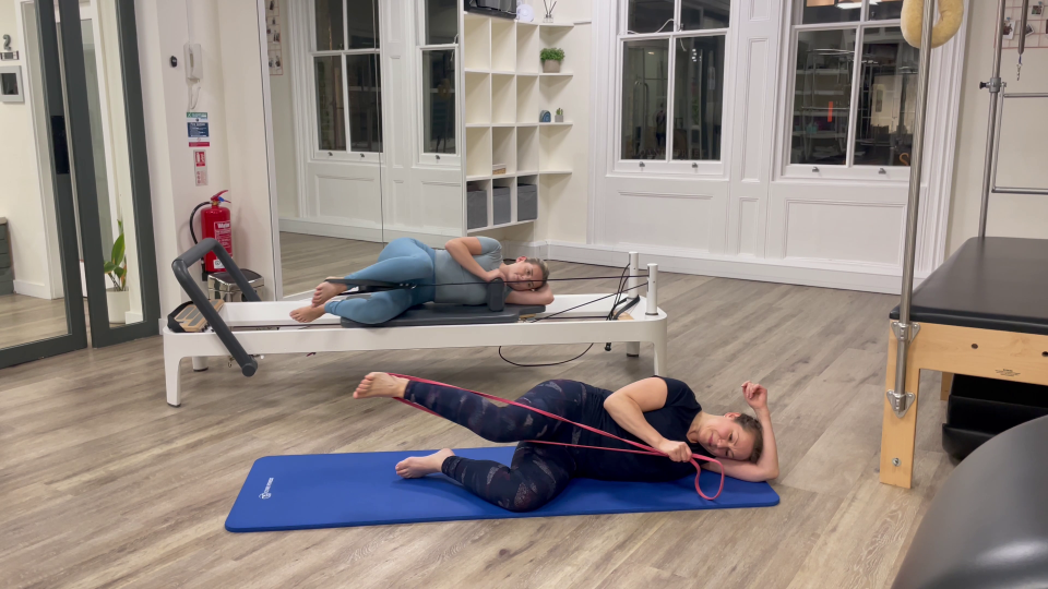 Two women performing Pilates exercises using resistance bands.
