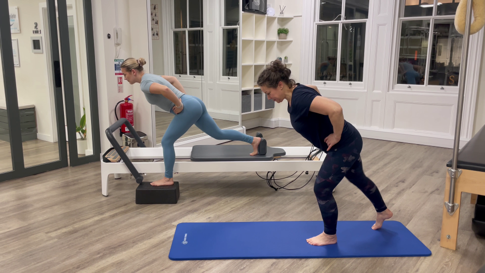 Two women performing Pilates exercises using a reformer.