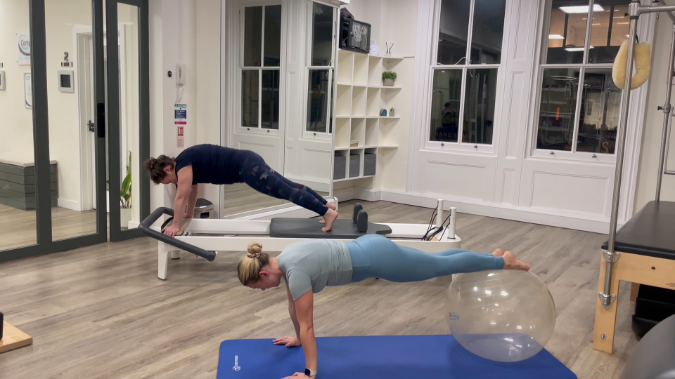 Two women performing Pilates exercises using a reformer and a stability ball.
