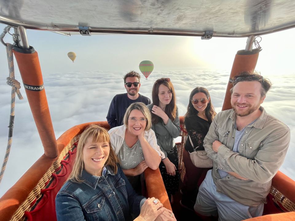 Group of friends enjoying a hot air balloon ride above the clouds.