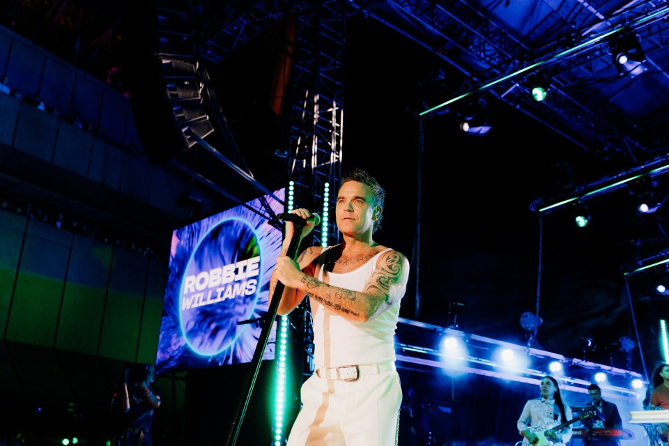 Robbie Williams performing on stage.