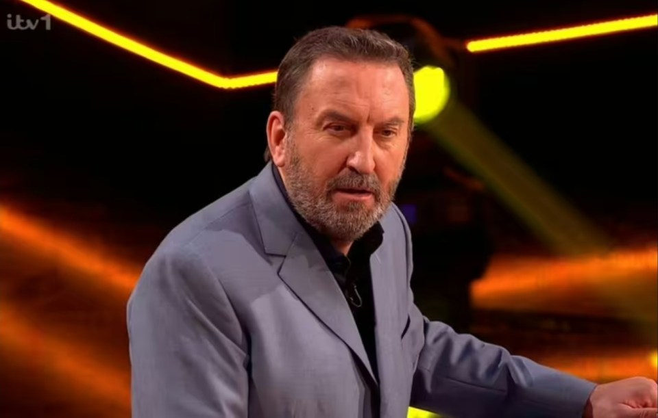 A man in a gray suit looks serious.