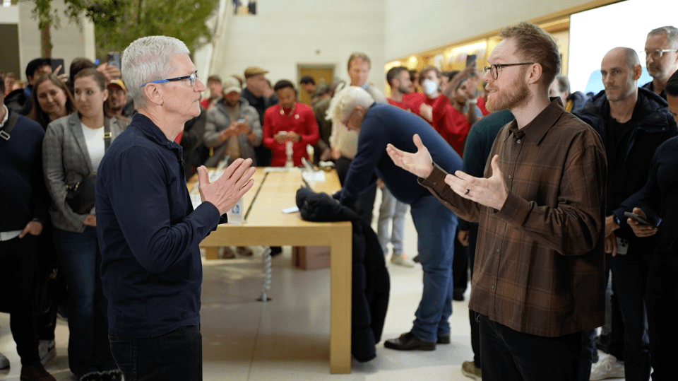 Tim Cook speaking with a man in an Apple Store.
