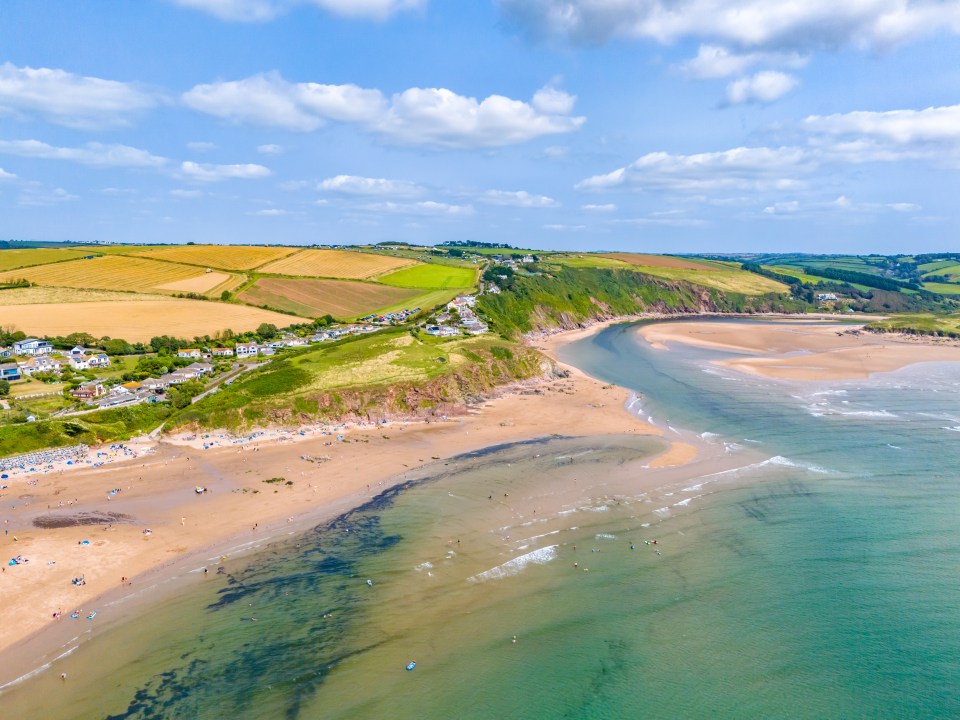 Aerial view of Bigbury-on-Sea beach in Devon, showing the sandy beach, the calm sea, and the surrounding landscape.