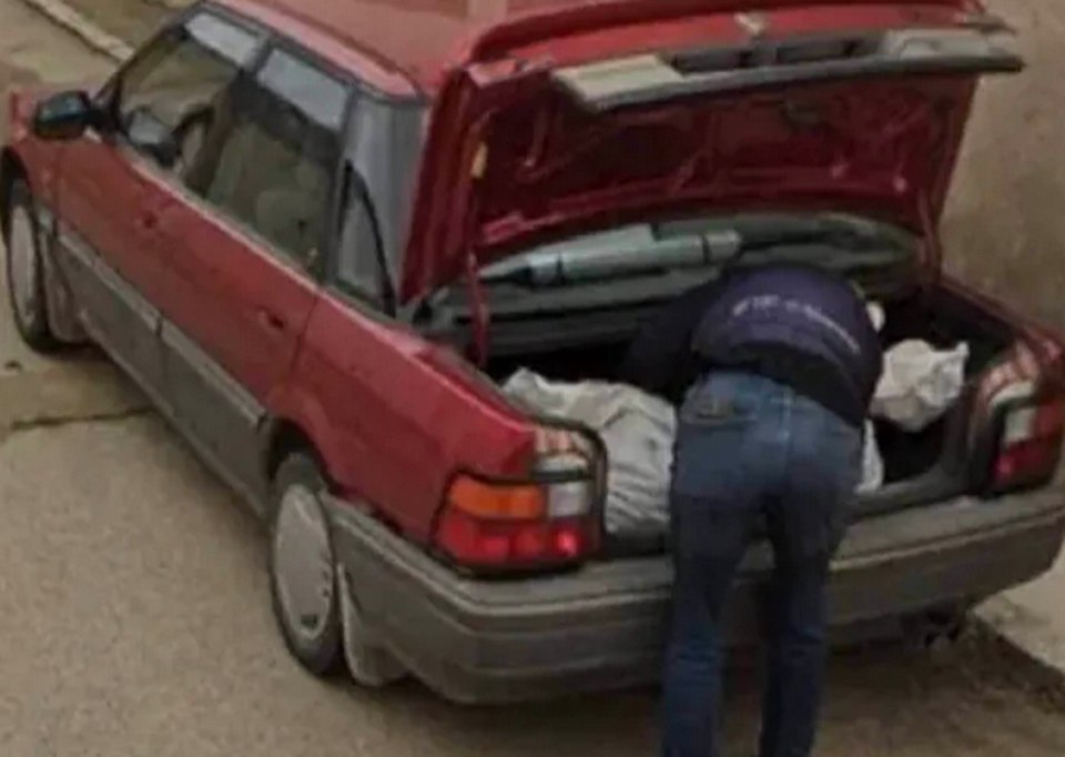 Google Street View image of a person placing a large white bag into a car trunk.