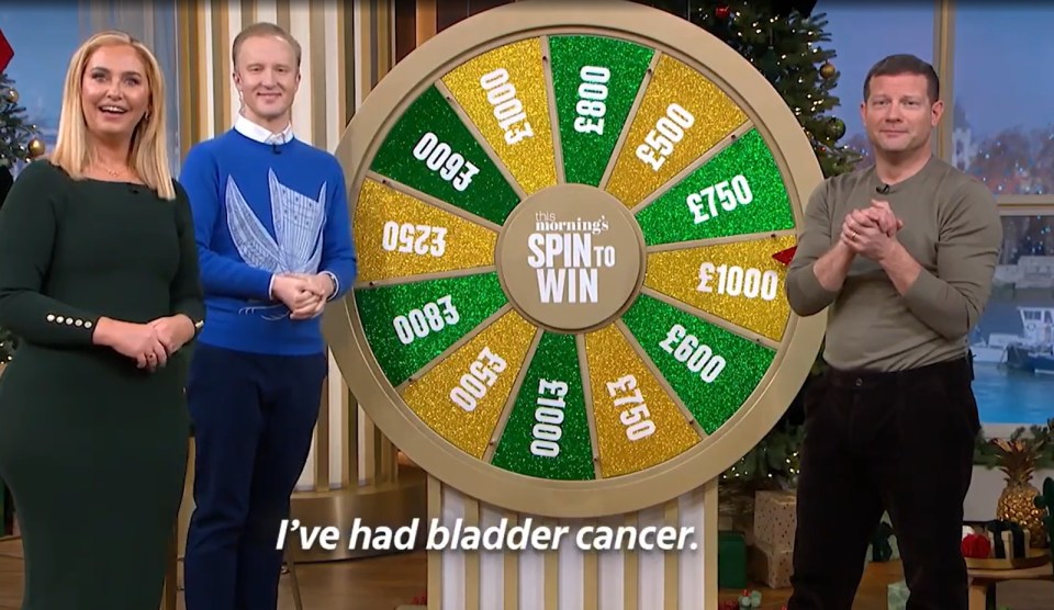 Three presenters stand by a "Spin to Win" wheel on a game show.