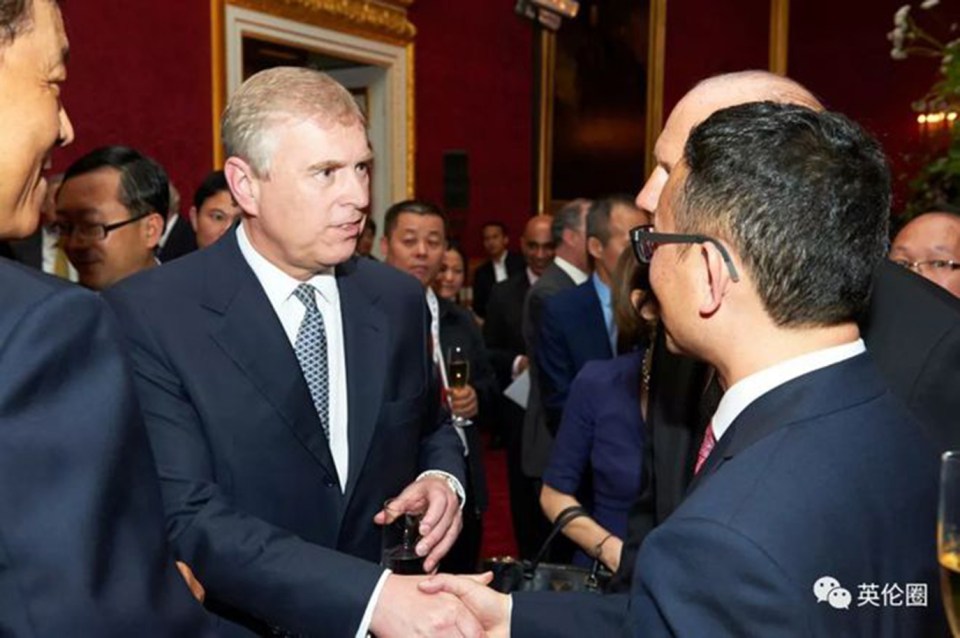 Prince Andrew shaking hands with a man in a suit.