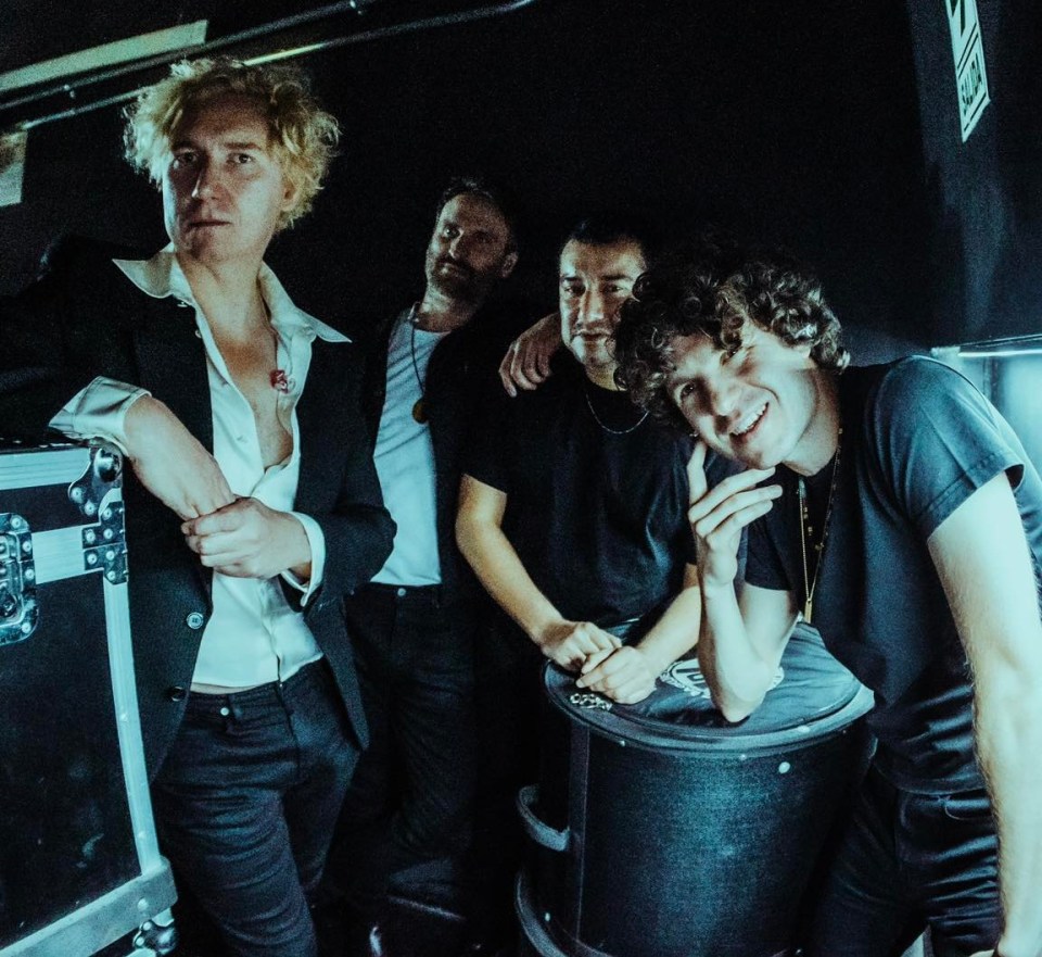 Four band members posing backstage.