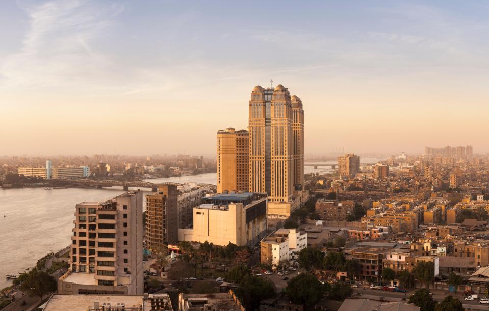 Cairo cityscape at sunset, featuring the Fairmont Nile City Hotel on the Nile River.