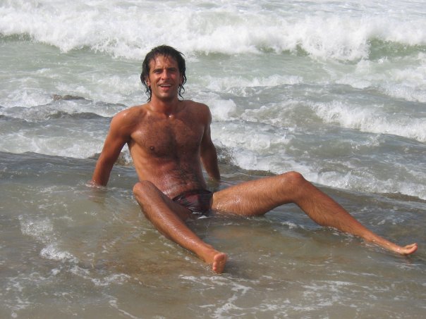 A man sits in shallow water near the shore.