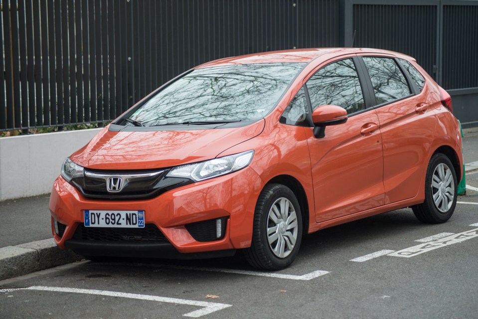 Orange Honda Jazz parked on a city street.