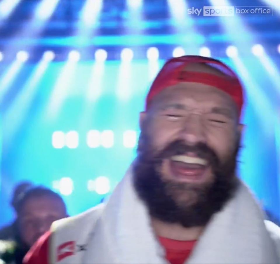 A jubilant, bearded boxer in a red cap and white robe.