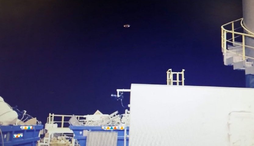Unidentified flying object over industrial site at night.