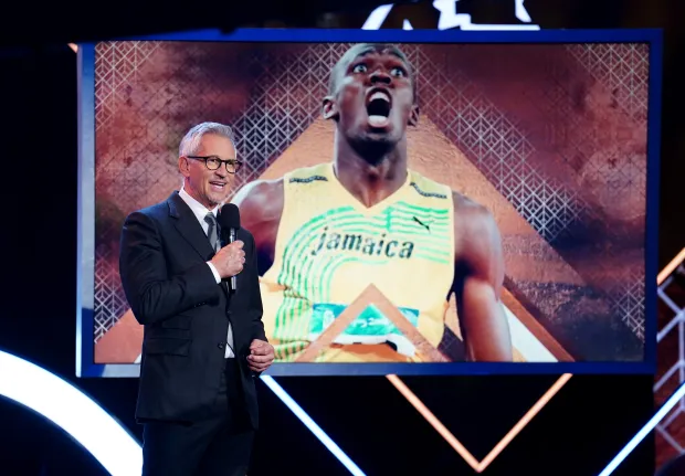 A man speaking at a podium in front of a large screen showing Usain Bolt.