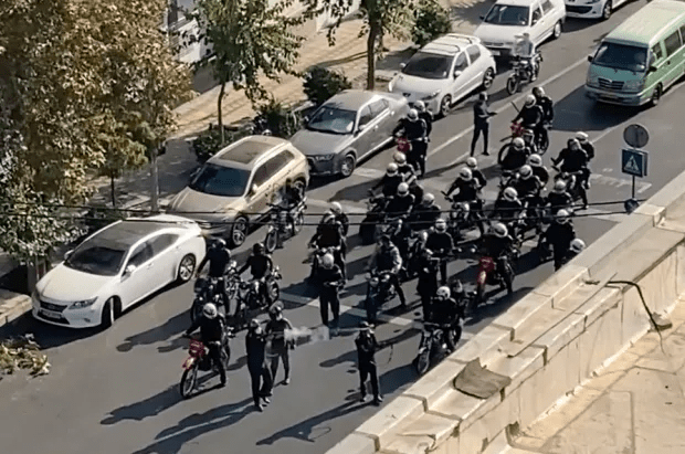 Riot police on motorcycles blocking a city street.