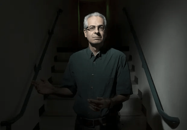 A man stands on a dimly lit staircase.