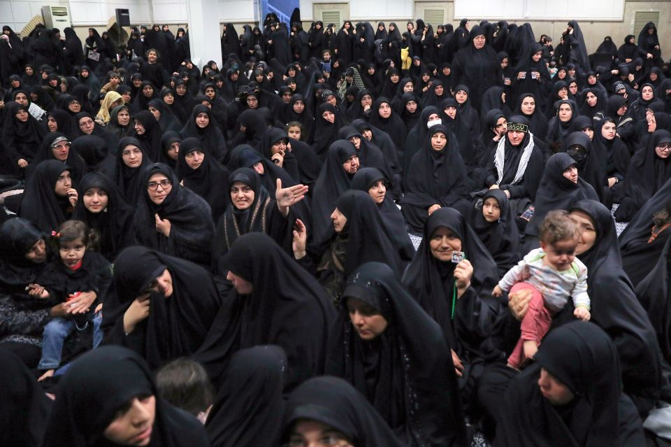 Large group of Iranian women in black chadors mourning.