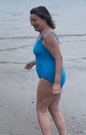 Lorraine Kelly in a blue swimsuit on a beach.