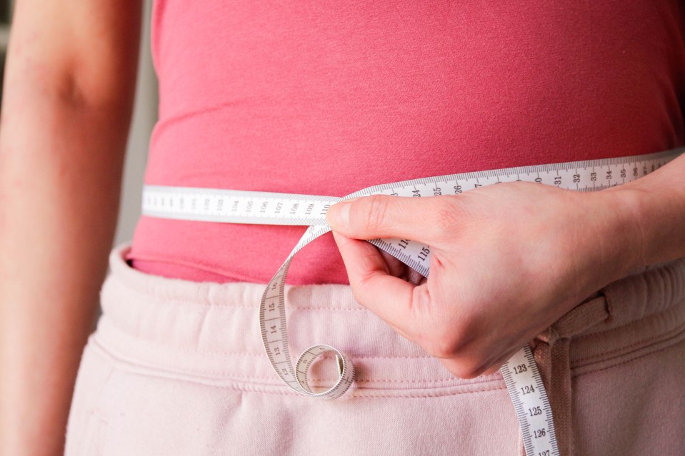 Woman measuring her waist with a tape measure.