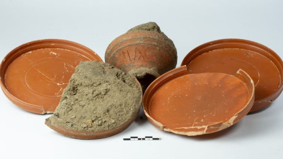 Archaeological find: broken Roman pottery and a jar with inscription.