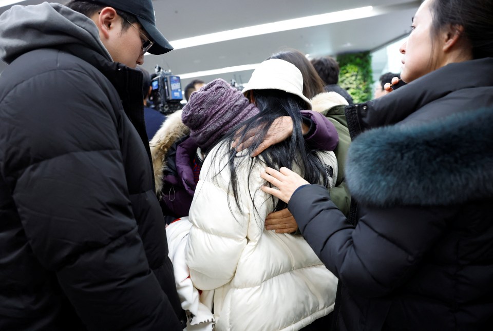 Relatives of a passenger comfort each other at an airport after a plane crash.