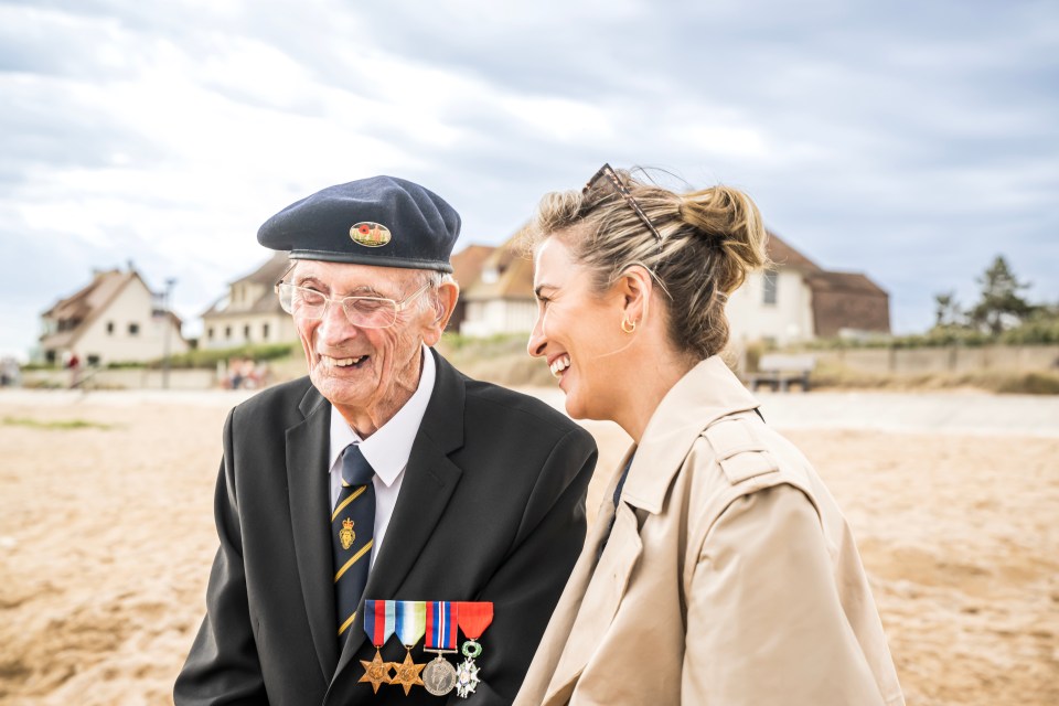 A smiling granddaughter and her decorated grandfather on a beach.