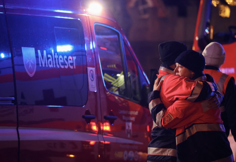 Two rescue workers embrace near a Christmas market following a car crash.