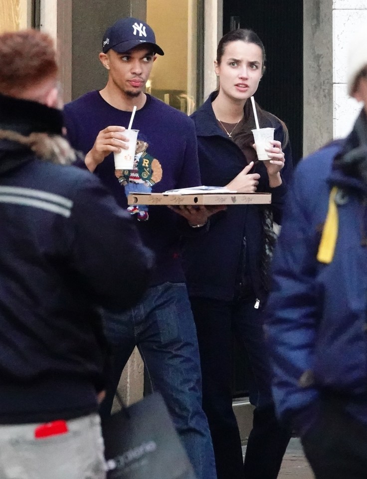Trent Alexander-Arnold and Estelle Behnke walking together, carrying drinks and pizza.