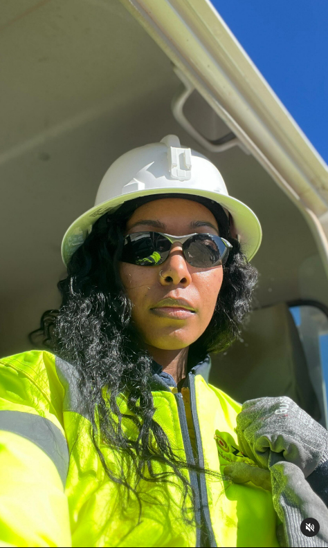 A female miner in a hard hat and safety glasses.