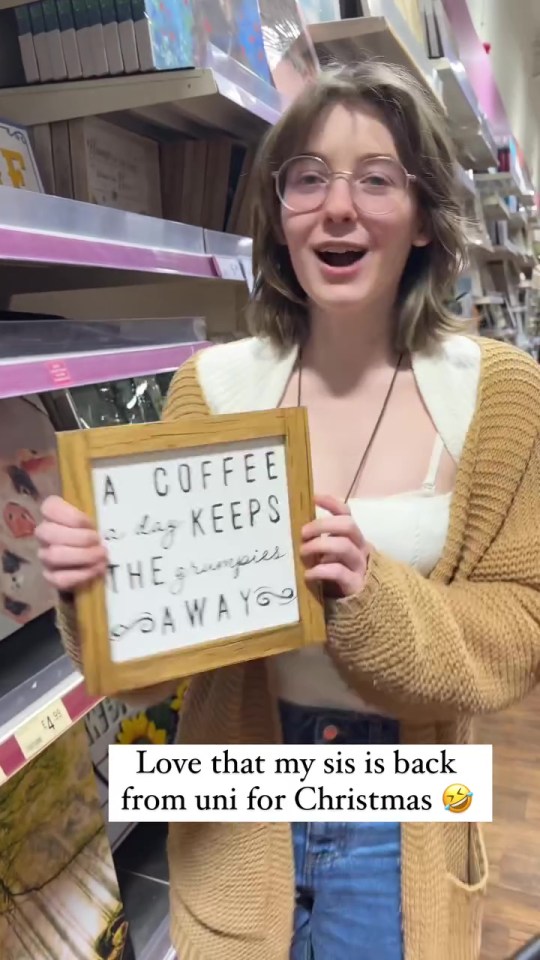 Woman holding a framed sign that says "A coffee a day keeps the grumpies away".