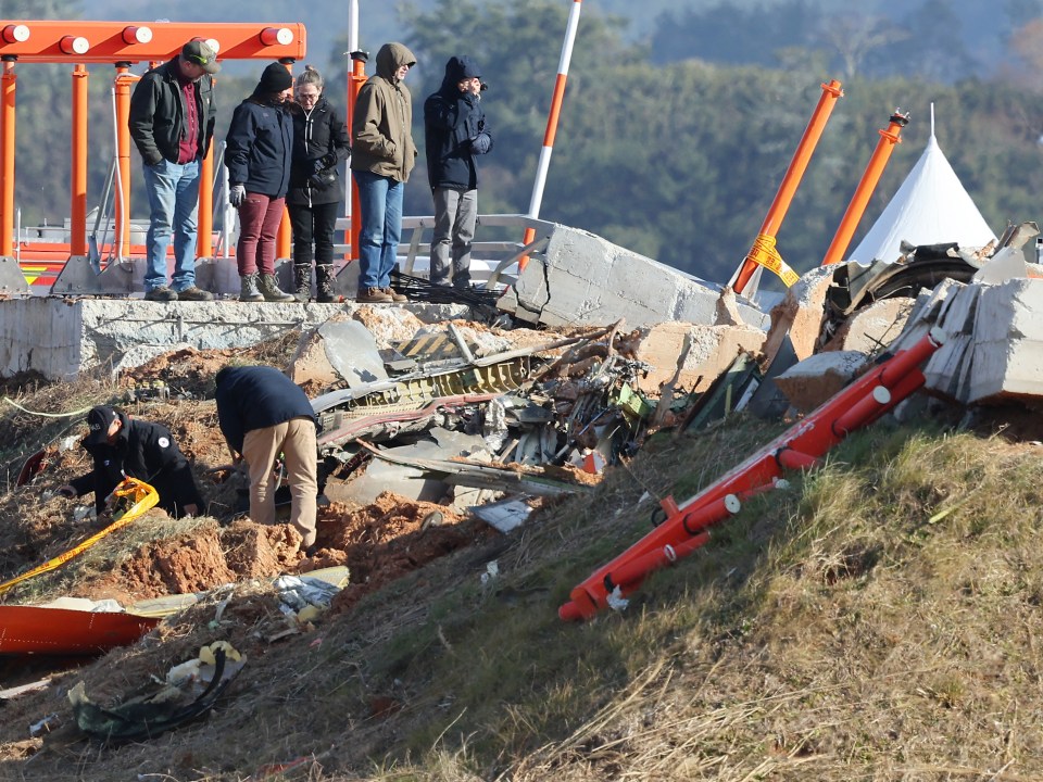 Investigators examine the wreckage of a plane crash at an airport.