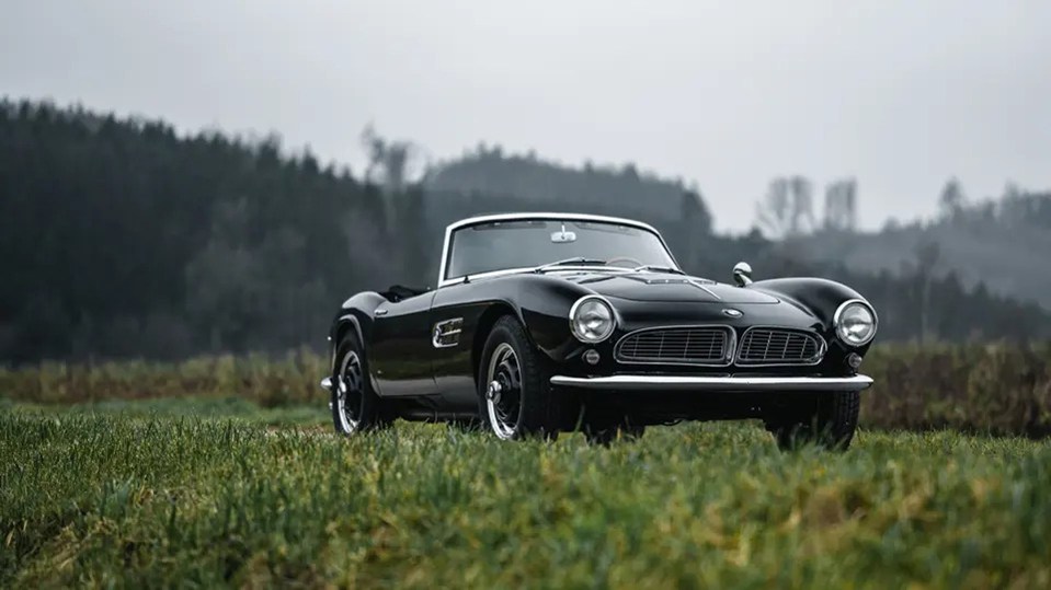 Black 1958 BMW 507 Roadster Series II in a field.
