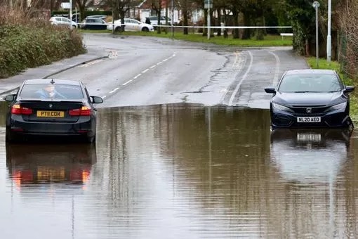 Flooded road with two cars partially submerged.