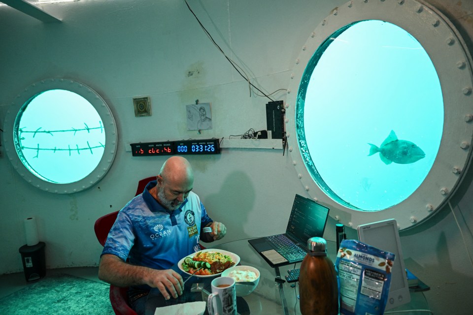 Man eating breakfast in an underwater habitat.