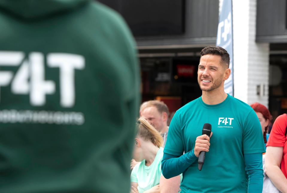 Man speaking into microphone at Food4Thoughts Wellness Festival.