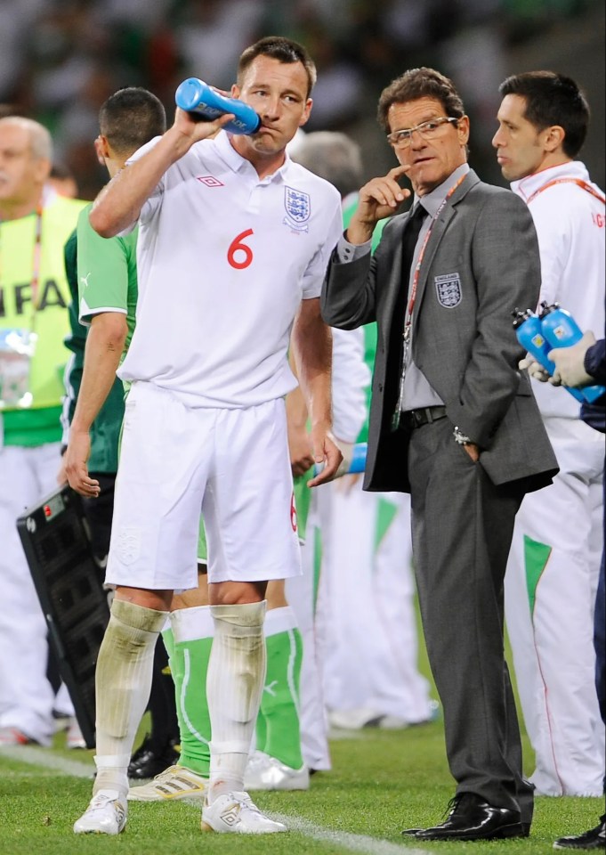 John Terry, England football player, drinks water while speaking with a coach.