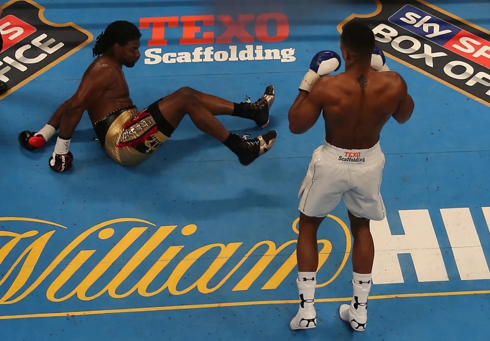 Boxer Charles Martin down on the canvas as Anthony Joshua stands over him.