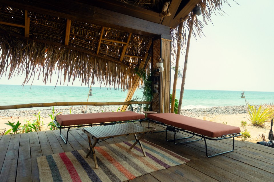 Beachfront patio with two fold-out cots and a small table.