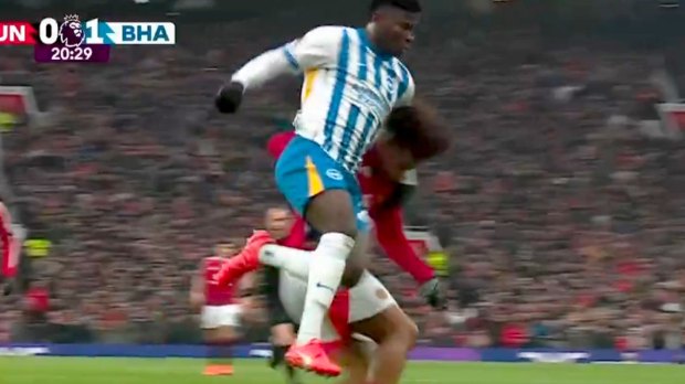 A Brighton player leaps over a Manchester United player during a soccer game.