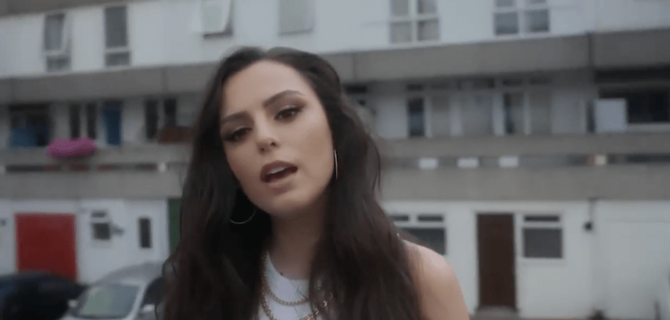 Woman with long dark hair speaking outdoors.