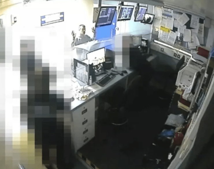 Screenshot of a man at a desk in an office, partially obscured by pixelation.